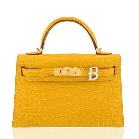 Yellow crocodile skin handbag with gold hardware on a white background, collection-preview
