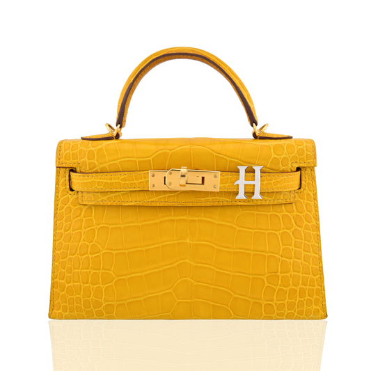 Yellow crocodile-patterned handbag with gold hardware on a white background, collection-preview