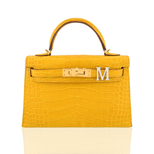 Yellow crocodile skin handbag with gold hardware on a white background, collection-preview