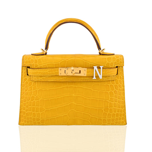 Yellow crocodile-patterned handbag with gold hardware on a white background, collection-preview