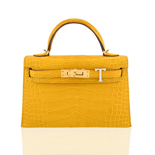 Yellow crocodile skin handbag with gold hardware on a white background, collection-preview