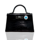 A luxury handbag with a black crocodile pattern and an 18kt gold, diamond, and mother of pearl evil eye design bijoux attached to it, collection-preview.