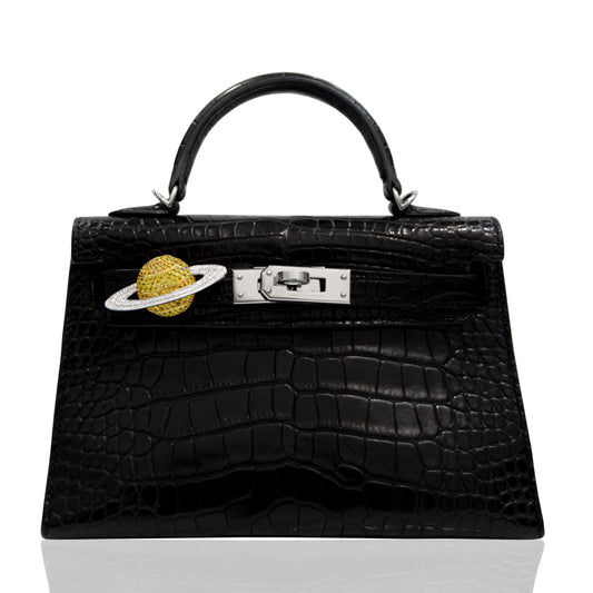 Black crocodile-patterned handbag with a gold planet charm on a white , collection-previewbackground