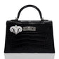 Black crocodile skin handbag with decorative clasp on a white background, collection-preview