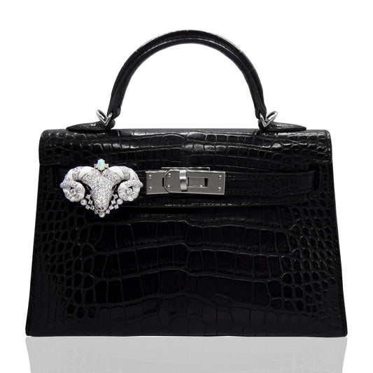Black crocodile skin handbag with decorative clasp on a white background, collection-preview