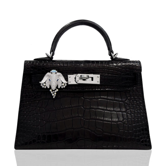Black crocodile skin handbag with a decorative clasp on a white background, collection-preview
