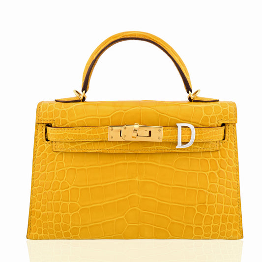 Yellow crocodile skin handbag with gold hardware on a white background, collection-preview