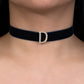 Black choker with a diamond 'D' clasp on a person's neck