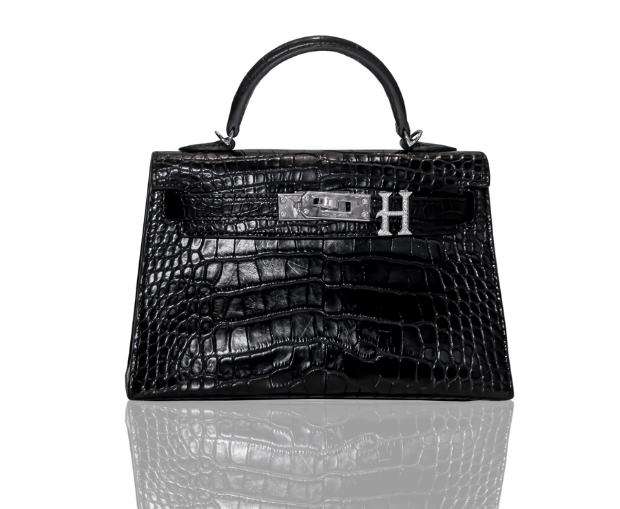 A black handbag with a crocodile pattern and a silver brooch with the letter 'H' on the front, collection-preview.