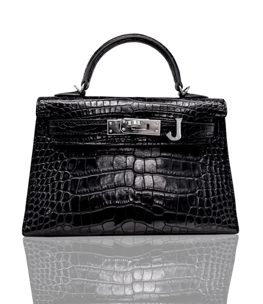 A black crocodile pattern handbag with a metallic 'J' logo emblem on the front, collection-preview.