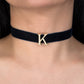 Navy velvet choker with gold letter 'K' on a person's neck