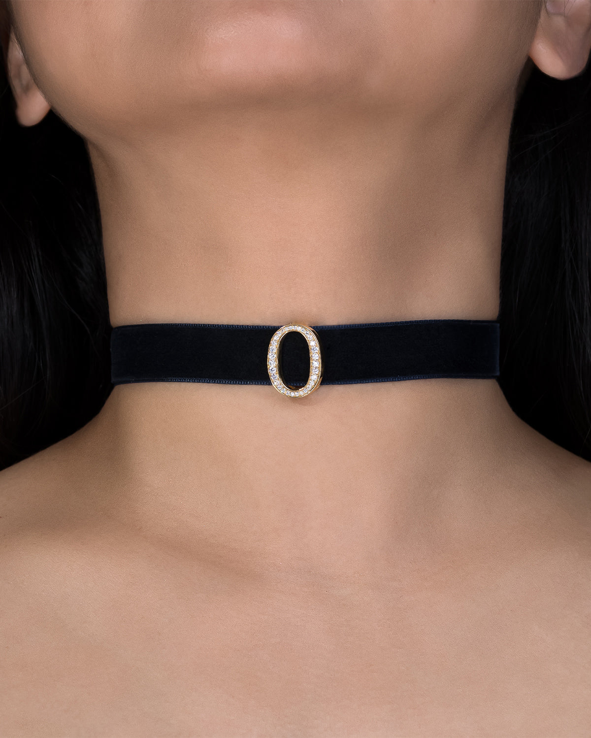 Black choker with a gold buckle worn by a person against a dark background