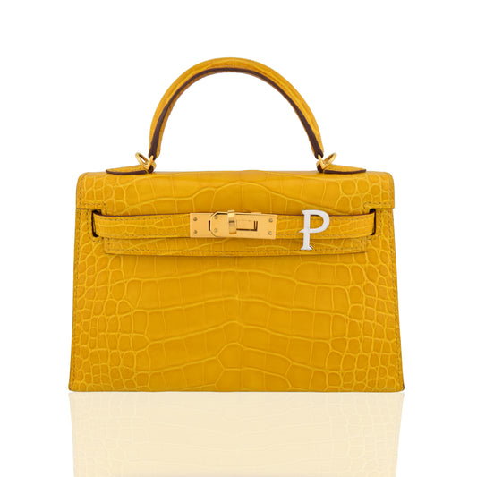 Yellow crocodile skin handbag with gold hardware on a white background, collection-preview