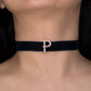 Black choker with a 'P' charm on a person's neck