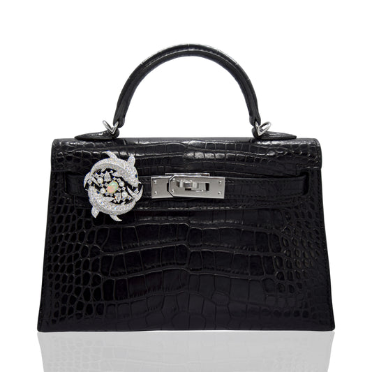 Black crocodile skin handbag with silver hardware on a white background, collection-preview