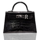 A black handbag with a crocodile pattern and a silver brooch with the letter 'R' attached to it, collection-preview.