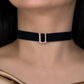 Black velvet choker with a silver buckle on a model wearing a gold top.