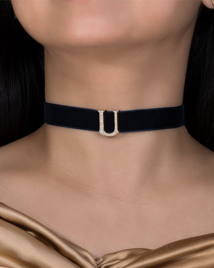Black velvet choker with a silver clasp on a person wearing a gold top.
