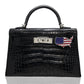A black crocodile pattern handbag with a USA flag accessory attached to it, collection-preview.