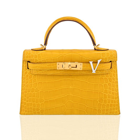 Yellow crocodile skin handbag with gold hardware on a white background, collection-preview