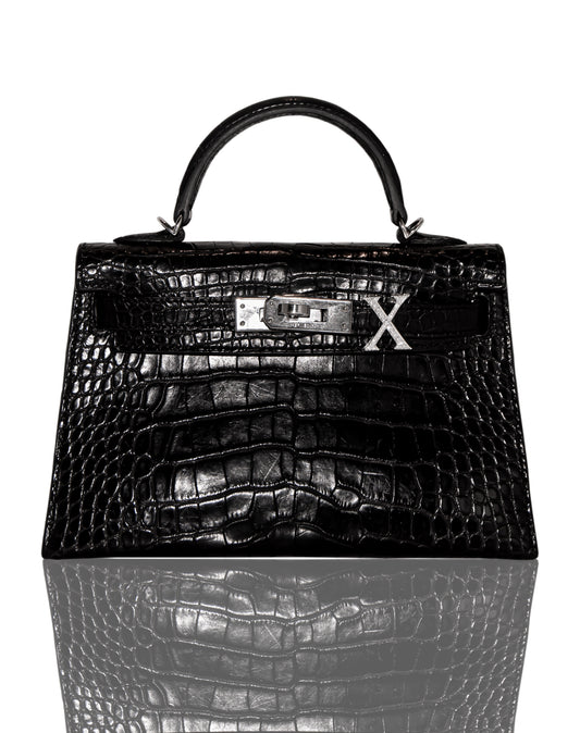 A black handbag with a crocodile pattern and a diamond-encrusted 'X' letter on the front, collection-preview.