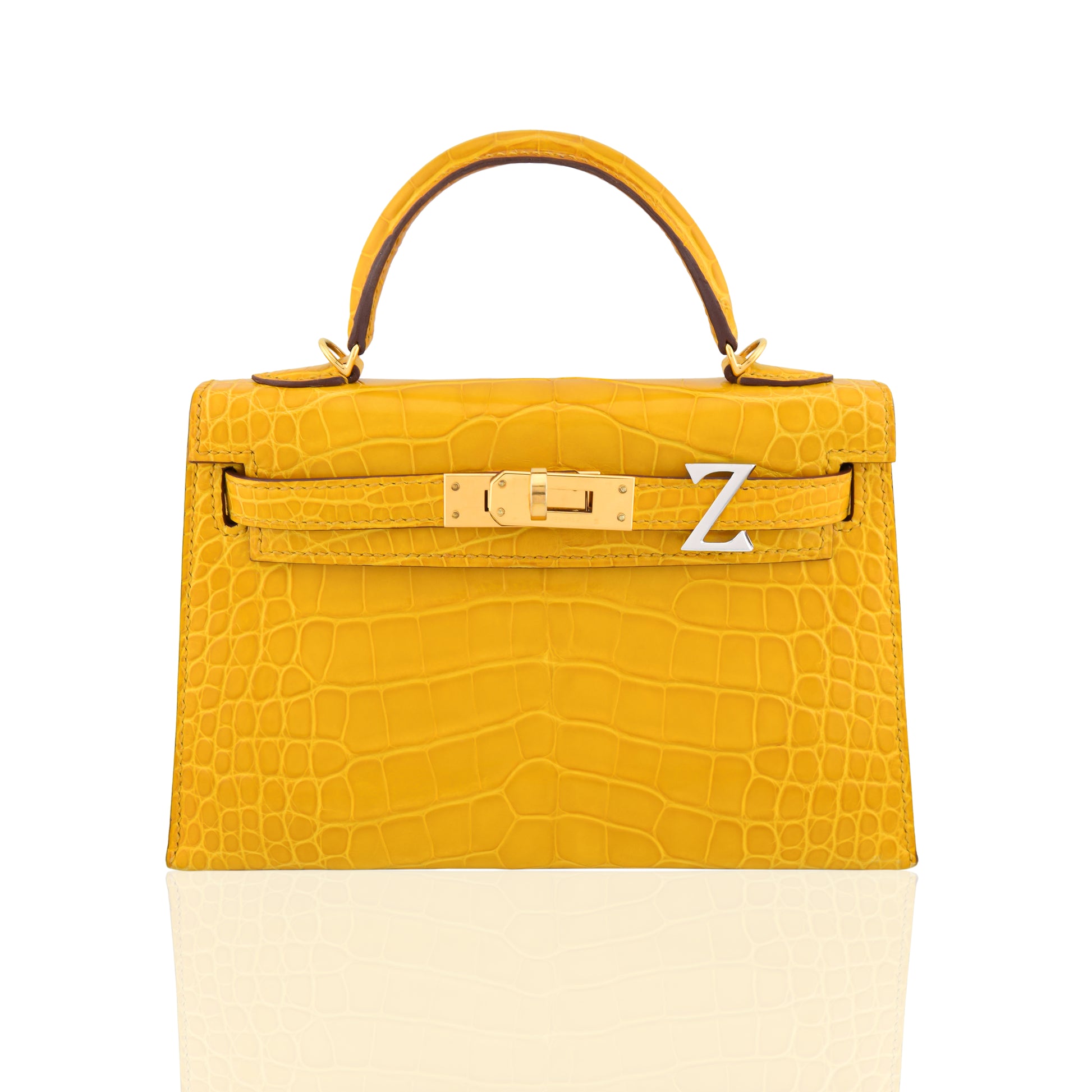 Yellow crocodile skin handbag with gold hardware on a white background, collection-preview